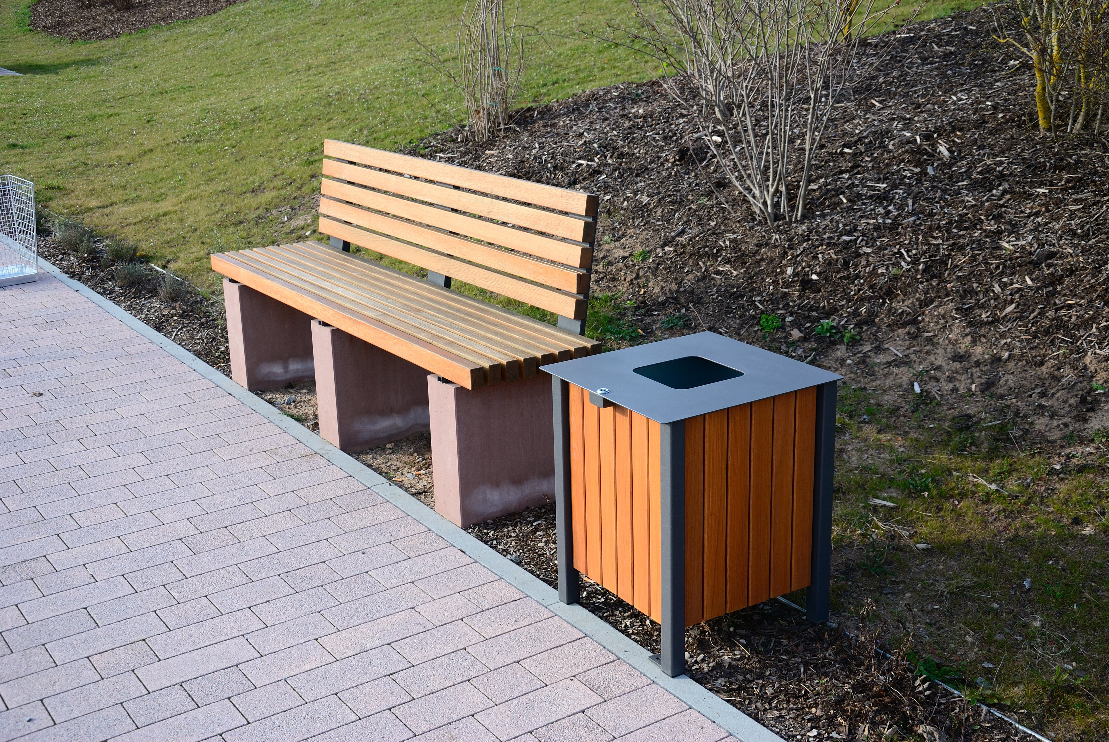Abfallbehälter mit Eichenholz-Verkleidung neben einer Bank aus Eichenholz